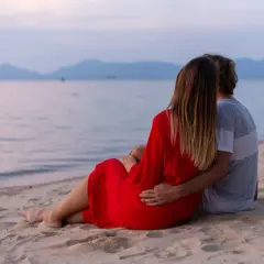 Para dla dwojga siedzi na plaży, patrząc na morze. To fajne miejsce nad morzem dla dwojga, idealne na romantyczny wieczór.