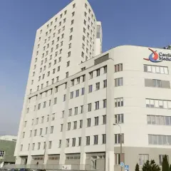 Nowoczesny budynek Carolina Medical Center w Warszawie z niebieskim krzyżem i napisem "Ostry Dyżur Ortopedyczny".