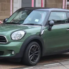 Zielony mini paceman stoi na ulicy, mokry od deszczu.
