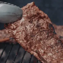 Soczysty stek na ruszcie, idealny do grillowania. Aromatyczny zapach unosi się w powietrzu, zapowiadając pyszną ucztę.