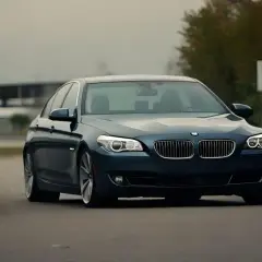 Ciemnoniebieskie BMW na drodze, może symbolizować odstąpienie od umowy kupna samochodu.