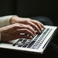 Dłonie piszą na laptopie, być może pracując nad zadaniem dla **windows modules installer worker**.