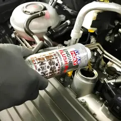 Mano enguantada vierte Liqui Moly Engine Flush para solucionar problemas de aceite.
