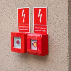 Dwa czerwone przyciski awaryjne z tabliczkami "Przeciwpożarowy wyłącznik prądu". Zgodnie z przepisami, są kluczowe dla bezpieczeństwa.