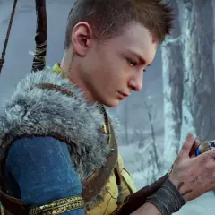 Atreus, zamyślony, trzyma w dłoni magiczny kamień. W tle zimowy las.