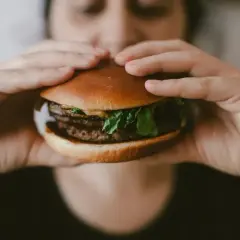 Zbliżenie na ręce trzymające soczystego burgera, idealnego na szybki posiłek. McRoyal makro.