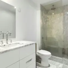 Modernt badrum med marmor, dusch och toalett. Enkel design som visar att det går att renovera badrum billigt med stil.