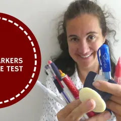 A woman smiles, holding a collection of colorful marking tools for sewing, ready to put them to the test.