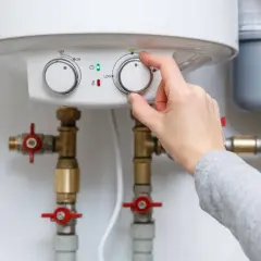 Main tenant ajuste le chauffe-eau pour éviter la pression d'eau chaude.