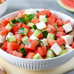 Erfrischender Melonensalat mit Mozzarella, Gurken und Minze in einer weißen Schüssel. Perfekt für heiße Tage!