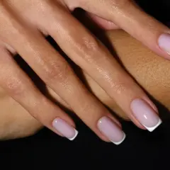 Dłonie z klasycznym french manicure – różowe paznokcie z białymi końcówkami.