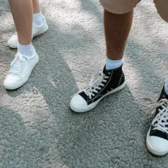 Białe i czarne trampki, idealne buty na długie marsze, stoją na szarej nawierzchni.