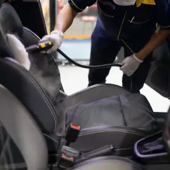Profesional usando vapor para limpiar los asientos del coche. El vapor ayuda a eliminar manchas y desinfectar.