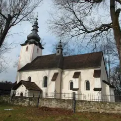 Kościół w Krościenku nad Dunajcem, z charakterystyczną wieżą i dachem, otoczony drzewami.