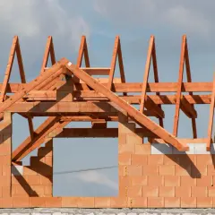 Drewniana konstrukcja dachu na budowie. Zastanawiasz się, ile kosztuje drzewo na dach? Oto widok szkieletu dachu z belek.