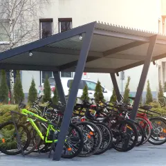 Zadaszona rowerownia w bloku, pełna rowerów gotowych do jazdy.