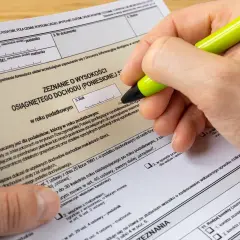 Dłoń z zielonym długopisem wypełnia formularz PIT-37.