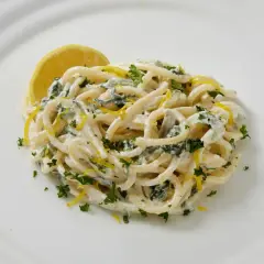Pâtes crémeuses au citron et persil, garnies d'une tranche de citron.