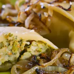 Maultaschen low carb gefüllt mit Gemüse, serviert mit karamellisierten Zwiebeln auf einem grünen Teller.