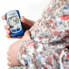 Gravid kvinna kontrollerar sitt blodsocker med en glukosmätare. En viktig del av att hantera graviditetsdiabetes.