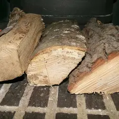Trois bûches de bois de chauffage, prêtes à être consumées, dégagent l'essence de bois de chauffage.
