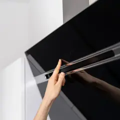 Mano tocando controles táctiles de campana extractora decorativa. Guía para como instalar una campana extractora decorativa.