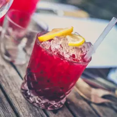 Czerwony drink z lodem i cytryną, prawdopodobnie z dodatkiem grenadyny. Co to jest grenadyna? Syrop z granatów, nadaje napojom piękny kolor i słodycz.