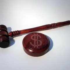 Młotek sędziowski z symbolem dolara na drewnianej podstawie. UFG kara za brak OC może być wysoka.