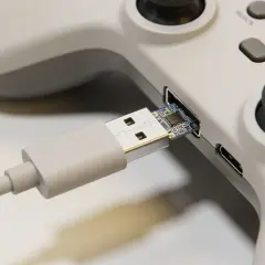 Szary kontroler z podłączonym kablem USB. Dowiedz się, jak podłączyć pada od PS4 do Xbox One, używając tego adaptera.
