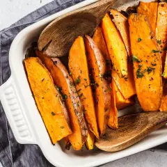 Pieczone bataty w ćwiartkach, posypane ziołami, gotowe do podania. Proste bataty przepis na pyszne danie.