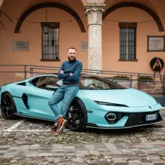 Mężczyzna opiera się o turkusowego Lamborghini Temerario na brukowanym dziedzińcu.