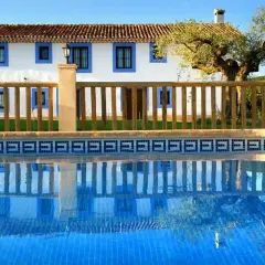 El cortijo Los Pradillos, con su piscina azul y reflejos, invita a un descanso bajo el sol andaluz.