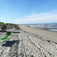 Una giornata di sole sulla spiaggia del Veneto. Ombrelloni colorati, lettini e il mare azzurro invitano al relax.