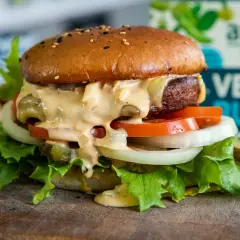 En saftig vegansk burgare med sallad, tomat, lök och picklad gurka, generöst toppad med krämig dressing. Perfekt för ett gott hamburgerdressing recept.