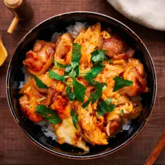 A delicious oyaku donburi recipe, featuring tender chicken and fluffy egg over rice, garnished with fresh parsley.