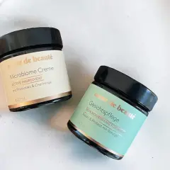 Zwei Tiegel "coeur de beauté" Microbiome Creme und Gesichtspflege, die auf probiotische Hautpflege setzen.