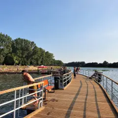 Ludzie odpoczywają i kąpią się nad zalewem Borki. Drewniane molo zaprasza do spacerów i podziwiania widoków.