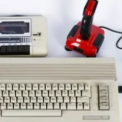 Commodore 64 z magnetofonem i joystickiem, idealny do tworzenia muzyki elektronicznej lat 80. zespoły.