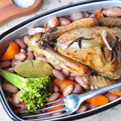 Ein köstlicher Braten von Tauben mit Bohnen, Karotten und Brokkoli, serviert in einer Auflaufform.