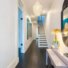 A stylish entryway table styled with a bust planter, palm leaf lamp, and a green tray. This setup offers inspiration on how to style an entryway table.