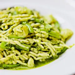 Leckere Trofie-Rezepte mit Pesto und grünen Bohnen auf einem weißen Teller.