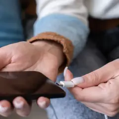 Dłoń podłącza kabel do telefonu. Zastanawiasz się, ile kosztuje wymiana baterii w telefonie?