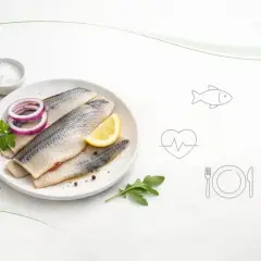 Talerze ze śledziami, cytryną i cebulą. Ikony ryby, serca i sztućców sugerują, czy śledzie są zdrowe.