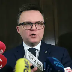 Polityk w okularach przemawia do mikrofonów. Liderzy partii politycznych często udzielają wywiadów mediom.