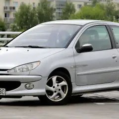 Srebrny Peugeot 206 1.4 benzyna na parkingu. Auto ma sportowy wygląd i jest w dobrym stanie.