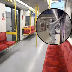 Wnętrze pustego wagonu metra na trasie M2. W okręgu pracownik w kombinezonie dezynfekuje drzwi.