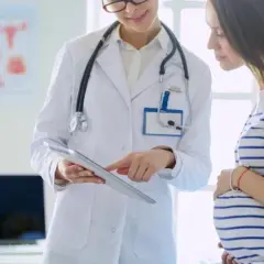 Lekarka omawia z ciężarną pacjentką znaczenie luteiny w ciąży, wskazując na tablet.
