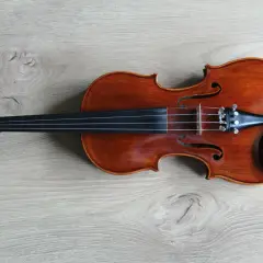 Eleganckie skrzypce leżą na drewnianym blacie. To instrument, który pozwala grać pierwsze skrzypce w orkiestrze, symbolizując lidera i główną melodię.