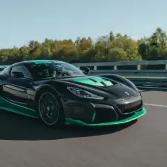 Czarny, sportowy, chorwackie auto elektryczne z zielonymi akcentami pędzi po torze wyścigowym.