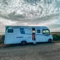 Kamper na wybrzeżu Szwecji, gotowy na przygodę. Dziecko w drzwiach zaprasza do środka. #szwecja #kamperem